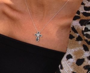 A woman wearing a cross necklace with leopard print.