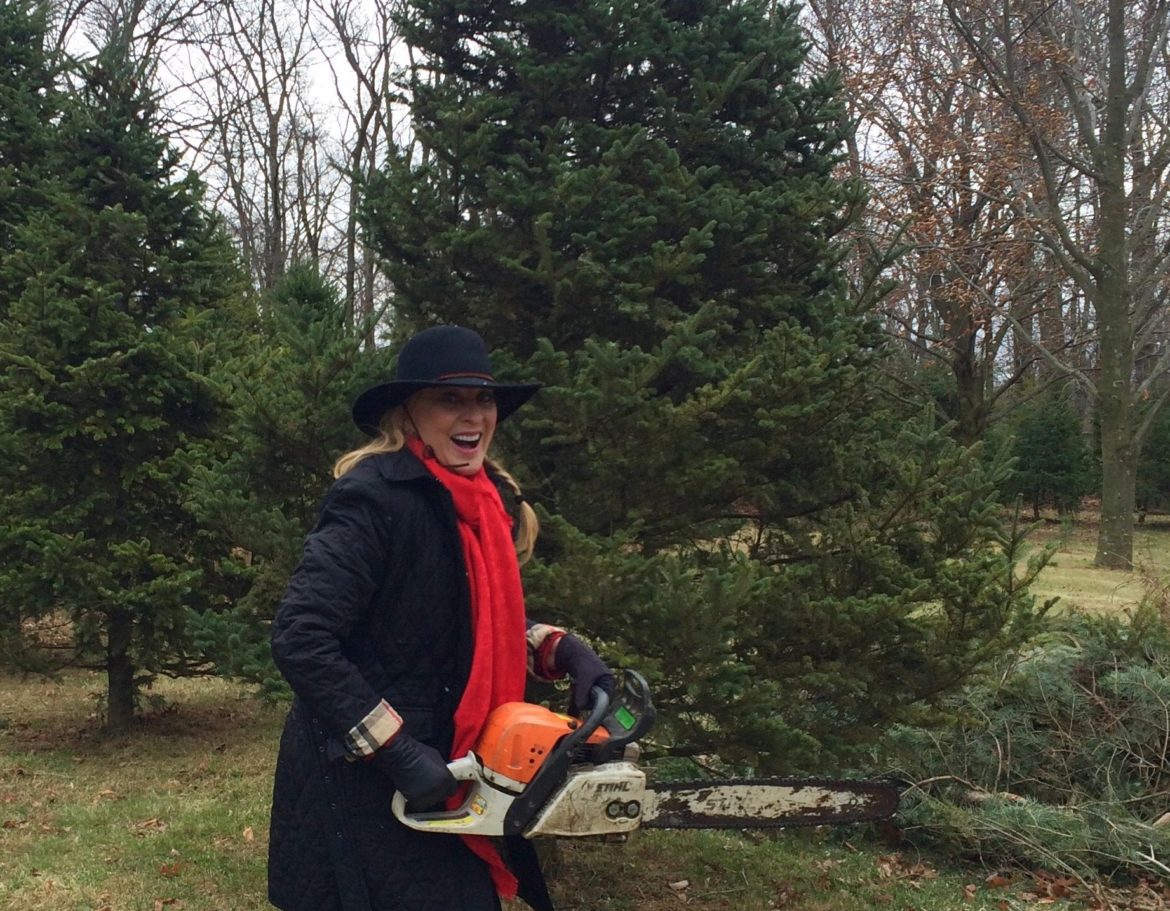 A woman holding an orange and a chainsaw.