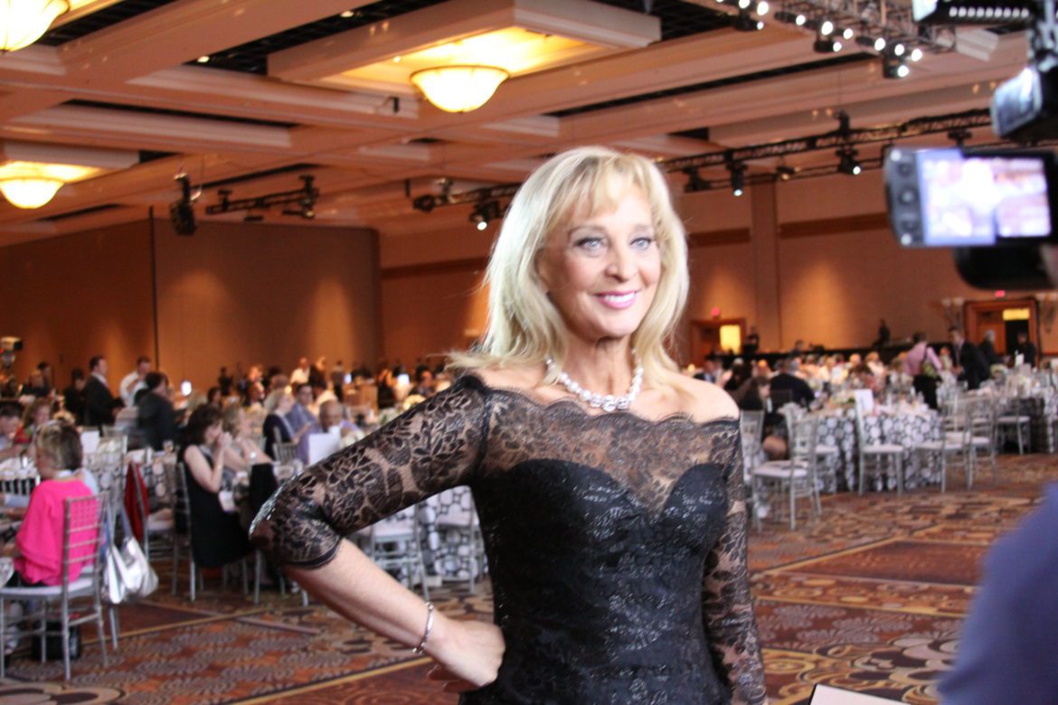 A woman in black dress standing next to tables.