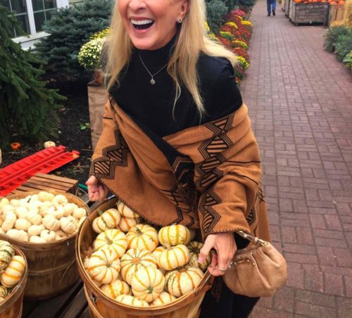 A woman holding a basket full of pumpkins.