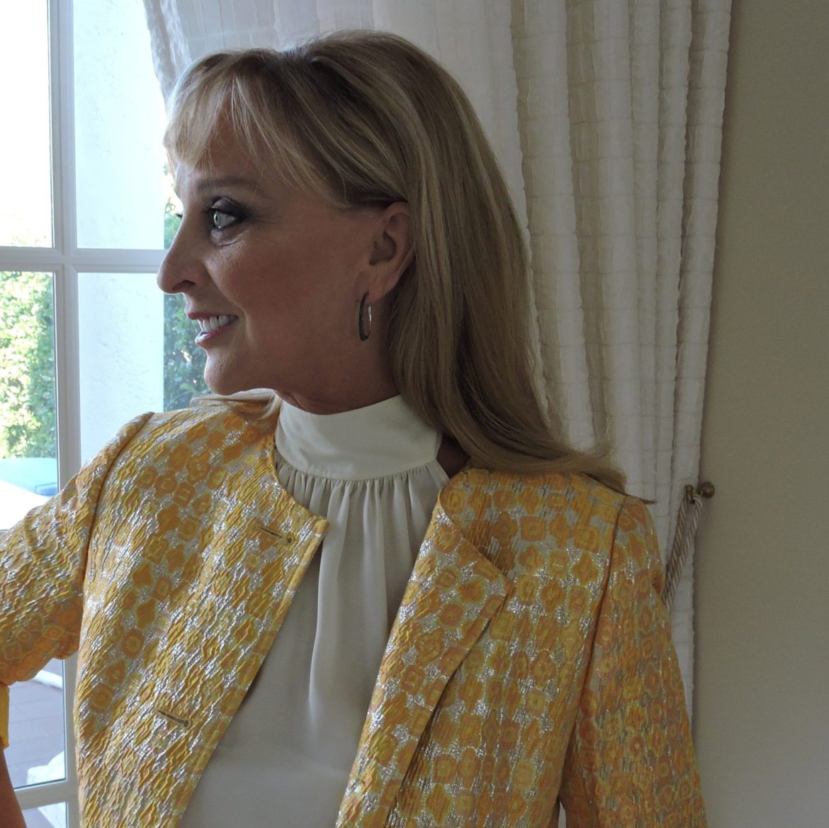 A woman in yellow jacket and white blouse.