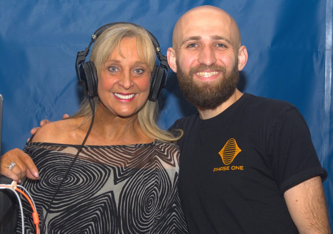 A man and woman with headphones on posing for the camera.