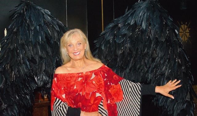 A woman in red is standing next to black feathers.